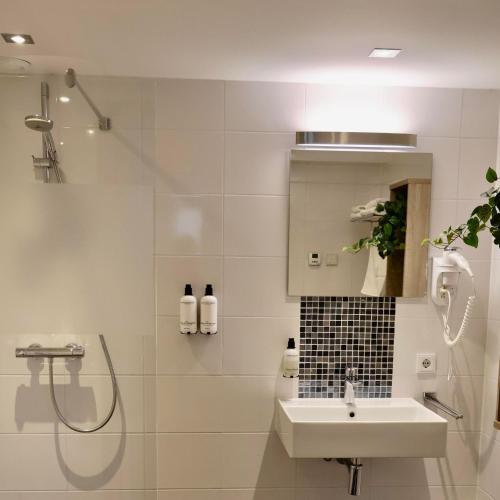 a white bathroom with a sink and a shower at Group Accommodation De Stoep in Appeltern