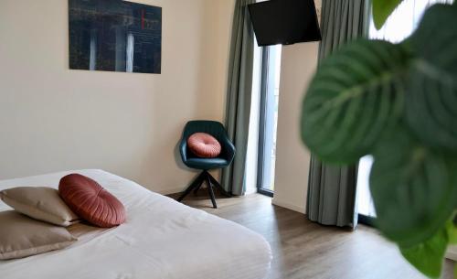 a bedroom with a bed with pillows and a chair at Vakantiewoning De Stoep in Appeltern