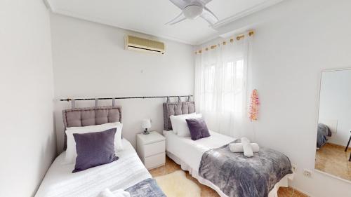 - 2 lits dans une chambre avec des murs blancs et des oreillers violets dans l'établissement Villa Pinos - A Murcia Holiday Rentals Property, à Sucina