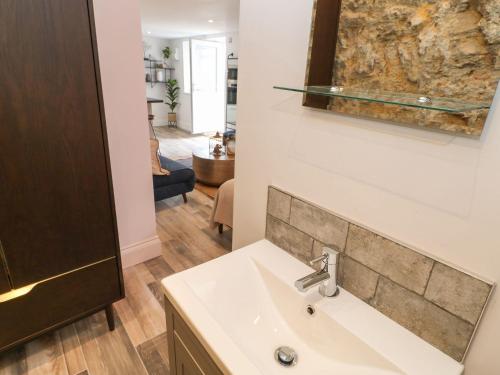 a bathroom with a sink and a living room at The Beach Apartment in South Shields