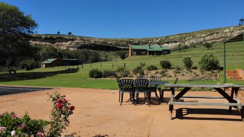 a picnic table and chairs with a house in the background at Pumula Guest Farm in Fouriesburg