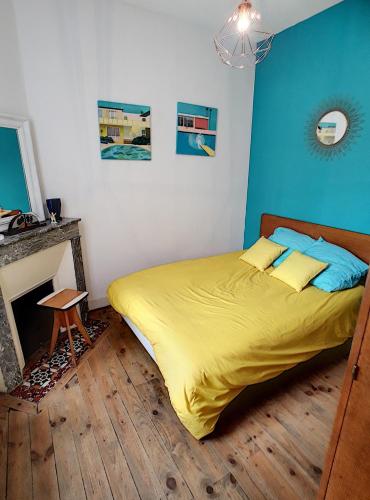 - une chambre avec un lit doté de draps jaunes et une cheminée dans l'établissement maison proche du centre et de la plage, à Soulac-sur-Mer