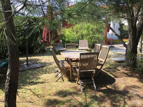 a wooden table and chairs in a yard at maison proche du centre et de la plage in Soulac-sur-Mer