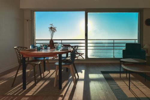 une salle à manger avec une table et une grande fenêtre dans l'établissement Appartement avec vue imprenable sur la baie des Sables d'Olonne et le chenal - 4 personnes, à Les Sables-dʼOlonne