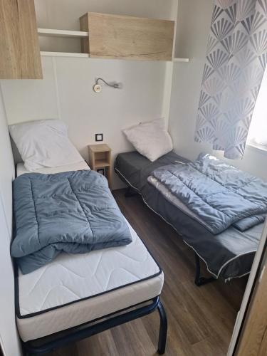 two beds in a small room with a bed on it at MH 535 Tout équipé 3 CHAMBRES 1 SDB dans camping 4 étoiles in Saint-Julien-en-Born