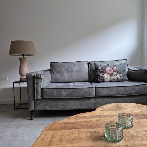 a grey couch in a living room with a table at Het Klokkenest in Katwijk aan Zee