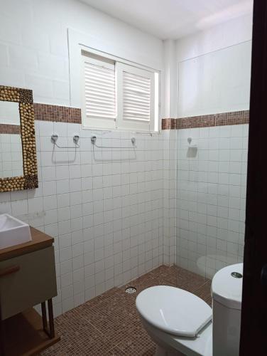 a white bathroom with a toilet and a sink at Aquavit pousada e comedoria in Jacumã