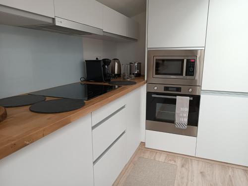 une cuisine avec des armoires blanches et des appareils en acier inoxydable dans l'établissement Location vacances, restriction un minimum de 7 nuits, à Cerbère