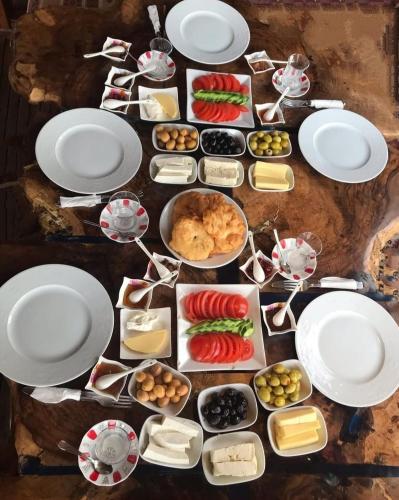 een tafel met witte borden en kommen eten bij Gökçeada Helios Pansiyon in Gokceada Town