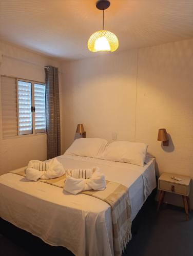 a bedroom with a large bed with towels on it at Aquavit pousada e comedoria in Jacumã