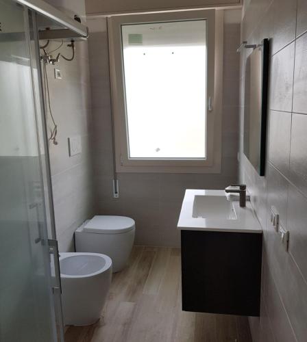 a bathroom with a toilet and a sink and a window at Dalila in Rosolina
