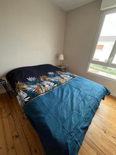 a bed with a blue comforter in a room at appartement entier quartier calme in Saint-Michel