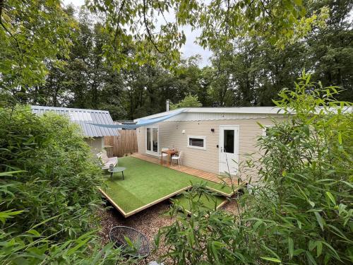a small white shed with a green yard at Cozy wooden cottage de Veluwe in Putten
