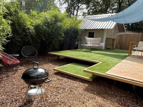 a backyard with a grill and a table with grass at Cozy wooden cottage de Veluwe in Putten