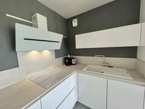 une cuisine avec des armoires blanches et un évier dans l'établissement Le Royal Rivage - Piscine - À 200m de la mer, à Carqueiranne