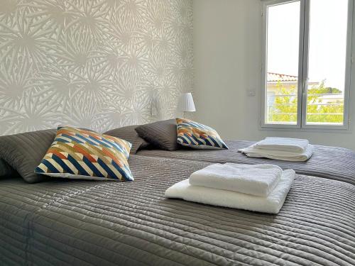 un grand lit avec deux oreillers dessus dans l'établissement Le Royal Rivage - Piscine - À 200m de la mer, à Carqueiranne