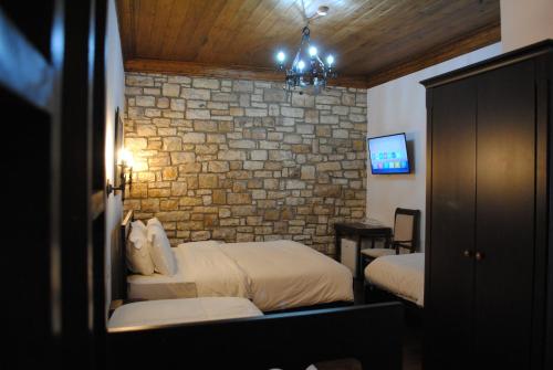 a bedroom with two beds and a brick wall at White House Boutique Hotel & Restaurant - since 1999 in Berat