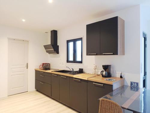 une cuisine avec des armoires noires et un comptoir dans l'établissement La Maison de la Mer, à Plobannalec-Lesconil