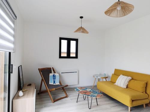 un salon avec un canapé jaune et une table dans l'établissement La Maison de la Mer, à Plobannalec-Lesconil