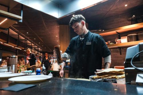 un hombre de pie en una cocina preparando comida en Belambra Clubs Les 2 Alpes Les Crêtes, en Les Deux Alpes