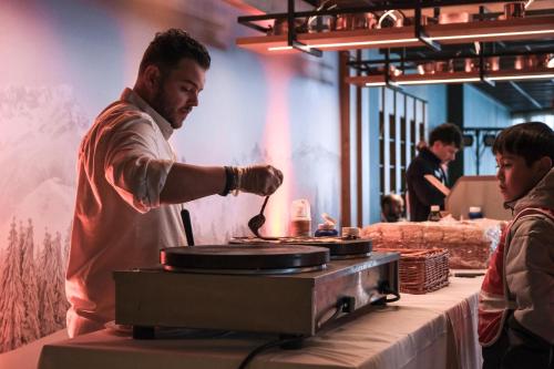un hombre cocinando comida sobre una parrilla en Belambra Clubs Les 2 Alpes Les Crêtes, en Les Deux Alpes