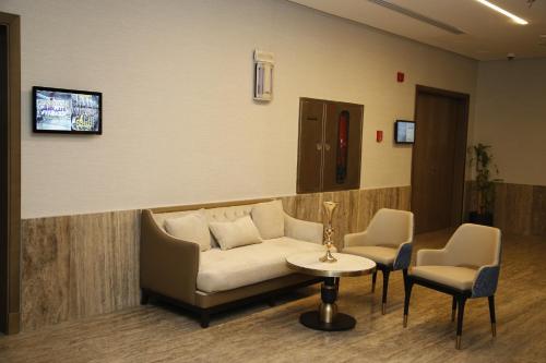 a waiting room with a couch and two chairs and a table at MADEN Al Rawda مادن الروضة in Al Madinah