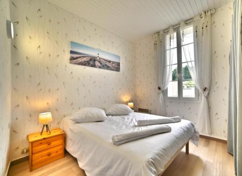 une chambre avec un lit blanc et une fenêtre dans l'établissement Le Fief des Roses, aux Mathes