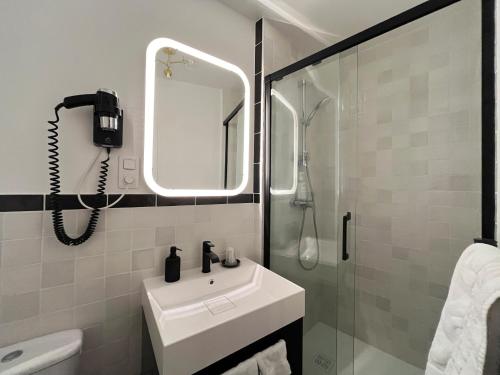 a white bathroom with a sink and a shower at Hôtel du Commerce in Cluny