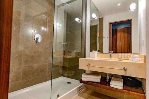 a bathroom with a shower and a sink and a tub at Courtyard by Marriott Santiago Airport in Santiago