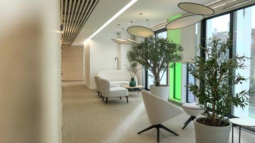 an office lobby with plants and chairs and windows at VISEU EXECUTIVE Hotel in Viseu