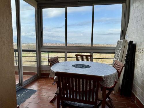 une table et des chaises dans une pièce avec une grande fenêtre dans l'établissement Appartement 2 pièces cabine 6 couchages ARGELES SUR MER AR200-098, à Argelès-sur-Mer