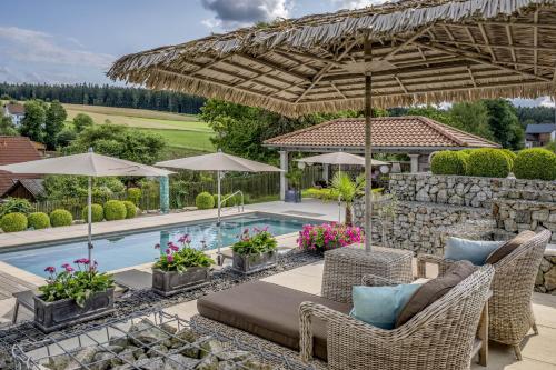 a patio with chairs and umbrellas next to a pool at Der Heindlhof in Neualbenreuth