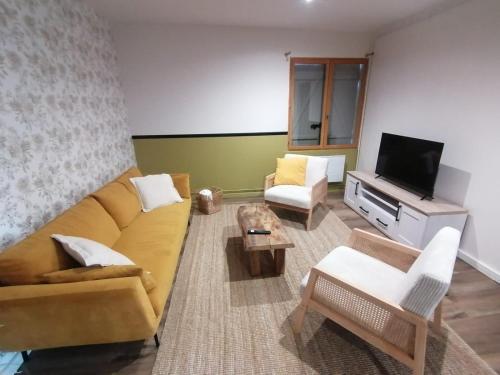 un salon avec un canapé et une télévision dans l'établissement Charmante maison, à Ardentes