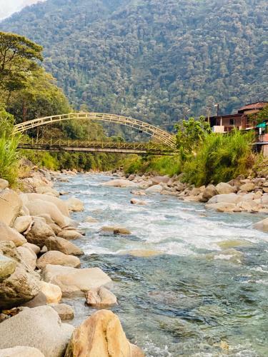 a bridge over a river with rocks and trees at Cabañas cerca de Baños de Agua Santa - RIO VERDE in Río Verde