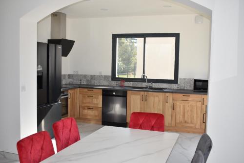 une cuisine avec une table blanche et des chaises rouges dans l'établissement La Villa du Sud, Arles Camargue, à Arles