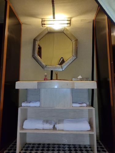 a bathroom with a sink with a mirror and towels at Erg Chebbi Star Camp in Merzouga