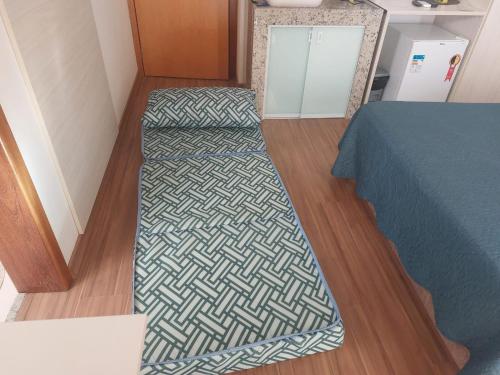 a room with a bed and a rug on a wooden floor at Flats da Júnia no Paris Residence in Lagoa Santa