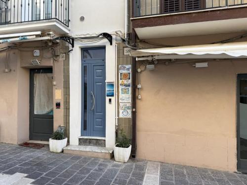 a blue door on a building with two plants at Residenza Antonio Casolino in Termoli
