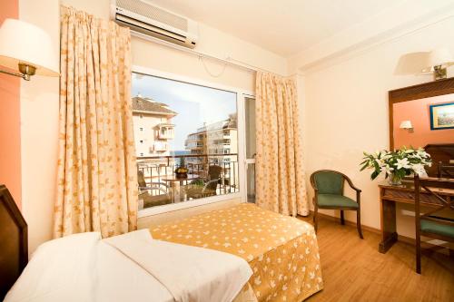 a bedroom with a window and a bed and a desk at Hotel Monarque Cendrillón in Fuengirola