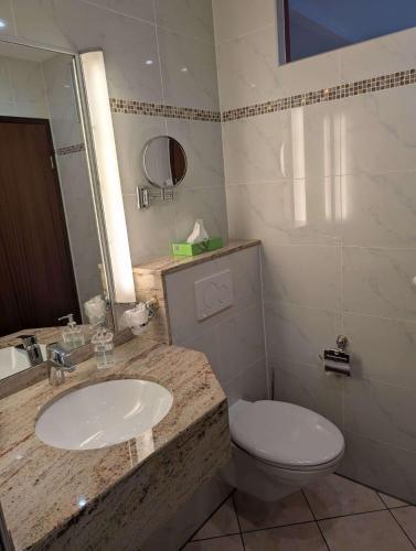 a bathroom with a sink and a toilet at Stadthotel Augsburg in Augsburg