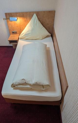 a bed with white sheets and pillows on it at Stadthotel Augsburg in Augsburg