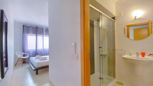un bagno con doccia, lavandino e specchio di Frente praia SIM T3 Praia Quarteira by HsRentals a Quarteira