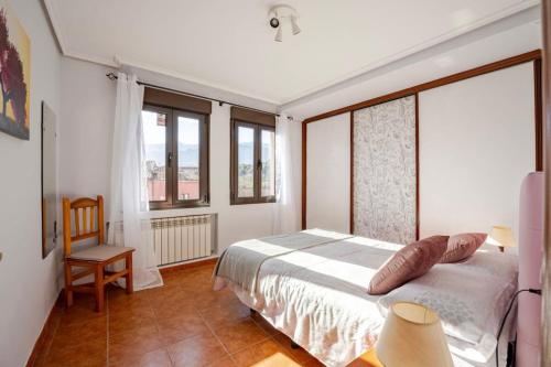 a bedroom with a bed and a chair and windows at Apartamento Esperanza de Llanes Selnatur in Llanes