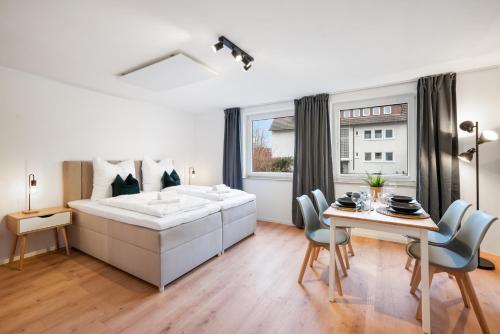 a bedroom with a bed and a table and chairs at LudwigsCozyEscape - Ruhiges Design-Apartment mit Balkon & Parkplatz, 4 Gäste, SmartTV in jedem Zimmer, Highspeed WLAN, Workspace, 24h Self Check-in in Ludwigsburg
