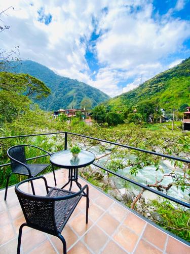 a table and chairs on a balcony with a view at Cabañas cerca de Baños de Agua Santa - RIO VERDE in Río Verde