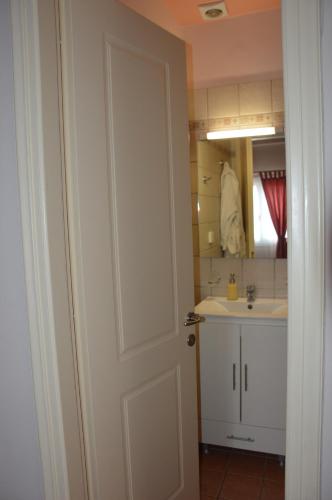 a bathroom with a white door and a sink at Akis Apartments in Paleokastritsa
