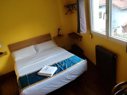 a bed in a yellow room with a window at Txoko Maitea Pentsioa in Urnieta