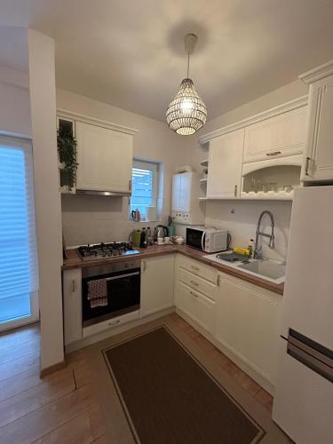 a kitchen with white cabinets and a sink at Serelor Cozy Flat in Dumbrăviţa