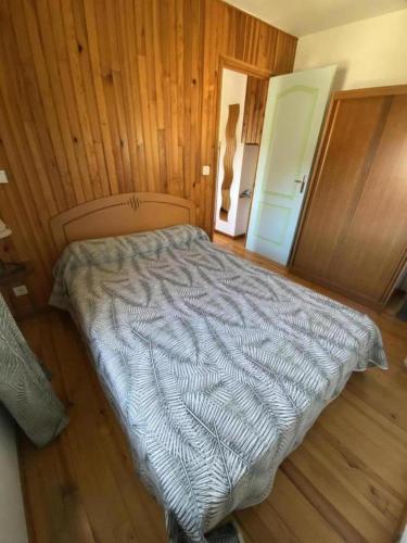 a bed in a room with wooden walls and wood floors at Gite Saint Guiral en pleine nature in Dourbies