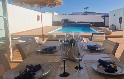 stół z kieliszkami do wina i basen w obiekcie Villa Nepal w mieście Playa Blanca